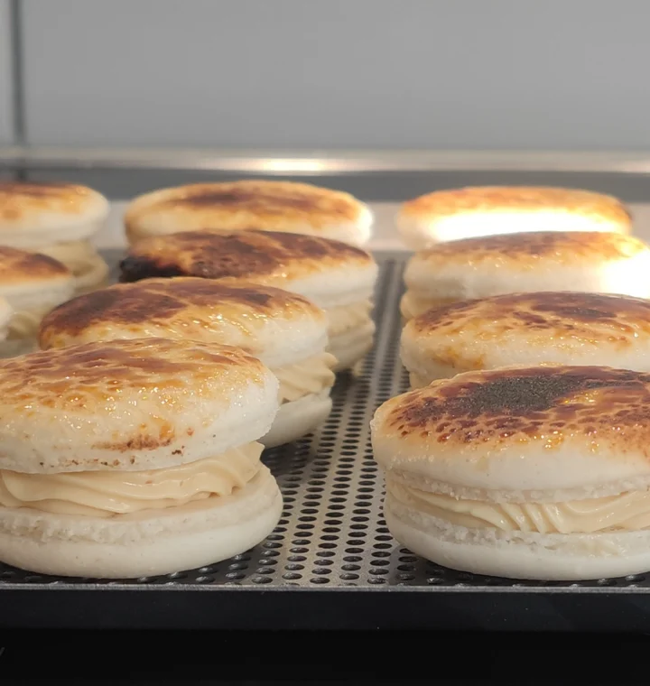 Huisgemaakte crème-brûléemacarons met gebrande bovenkant op de bakplaat