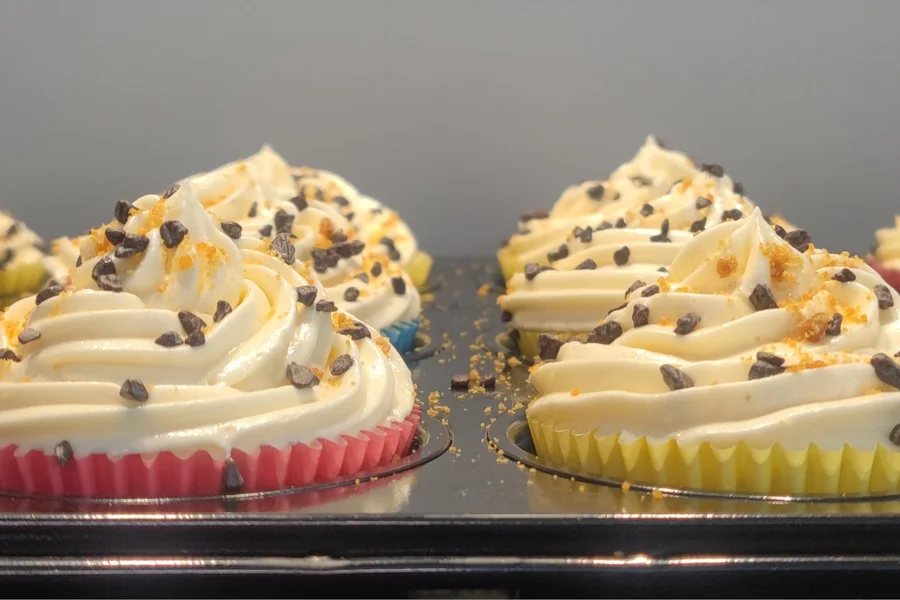 Versgebakken cupcakes met hoge crèmetoeven op een bakplaat