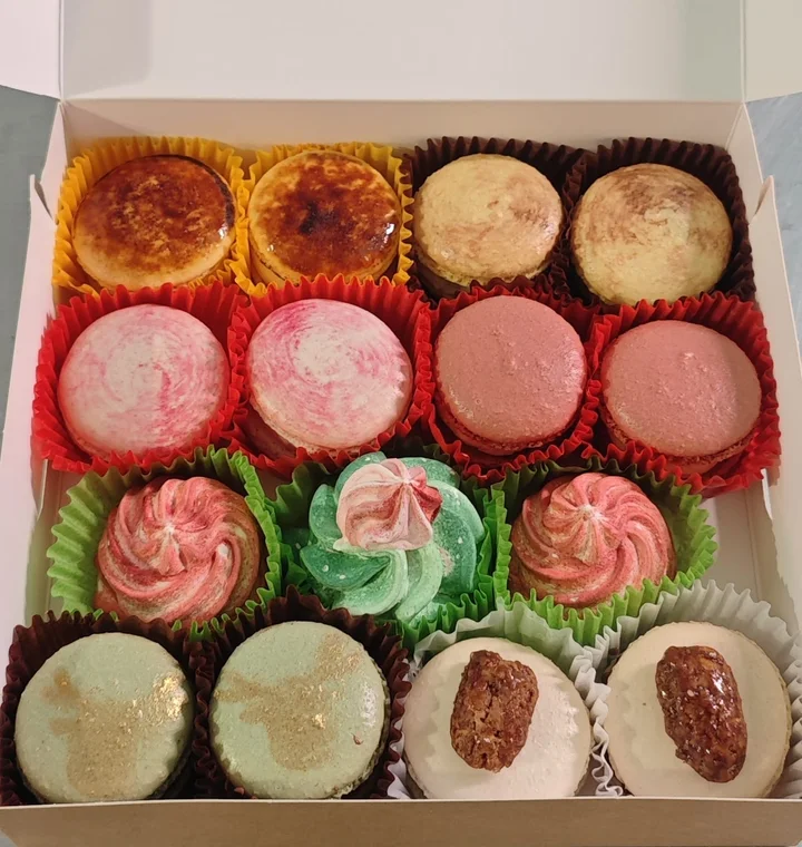 Een open doos met kleurrijke macarons en speels opgespoten vullingen