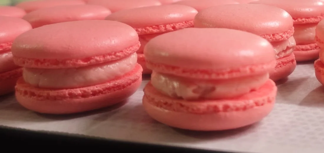 Roze macarons naast elkaar op de bakplaat in het thuisatelier