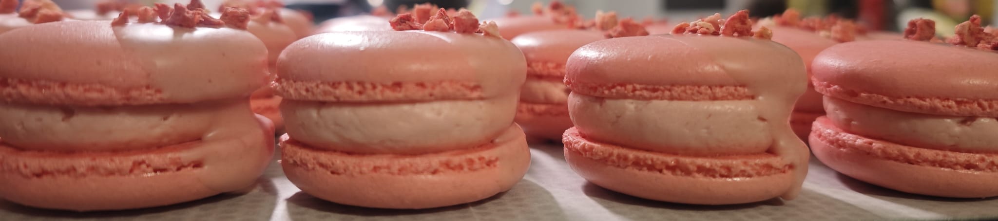 Versgevulde roze macarons, afgewerkt met kleine roze stukjes