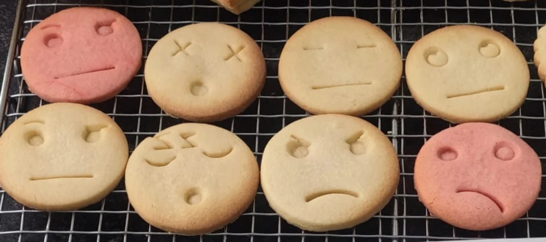 Eigen ronde koekjes in licht en roze deeg met verschillende ingedrukte gezichtsuitdrukkingen